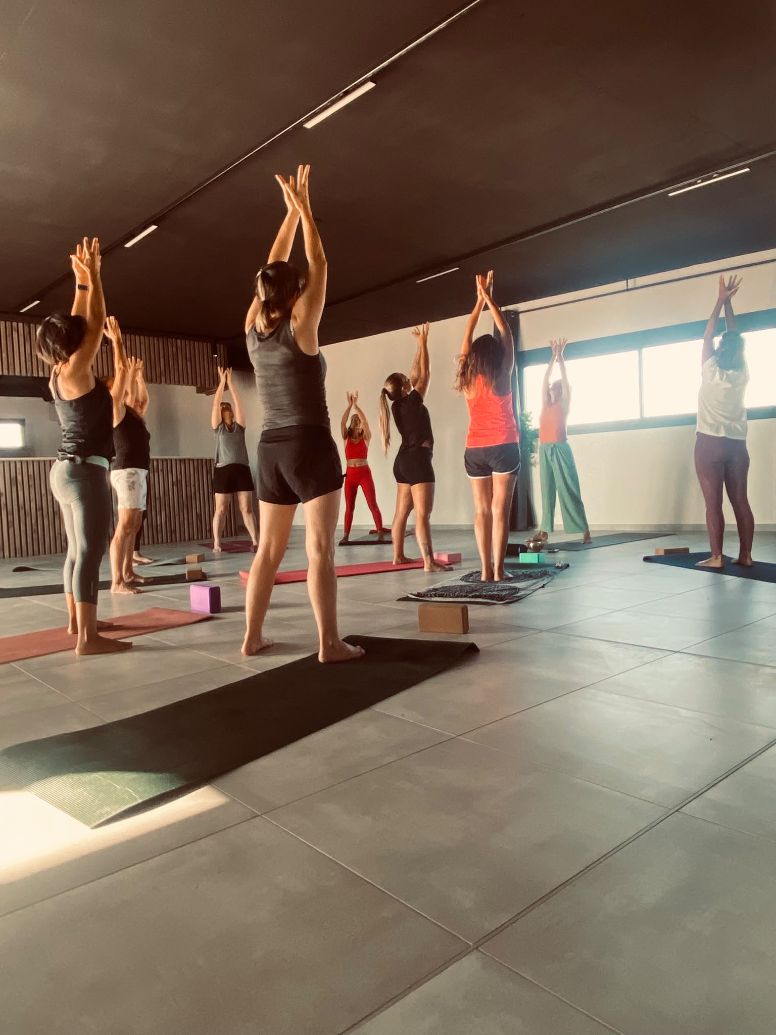 Cours collectif de yoga, salutation au soleil bras levés
